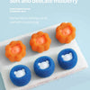 A collection of soft, orange and blue cleaning balls used for laundry, displayed on a white towel.
