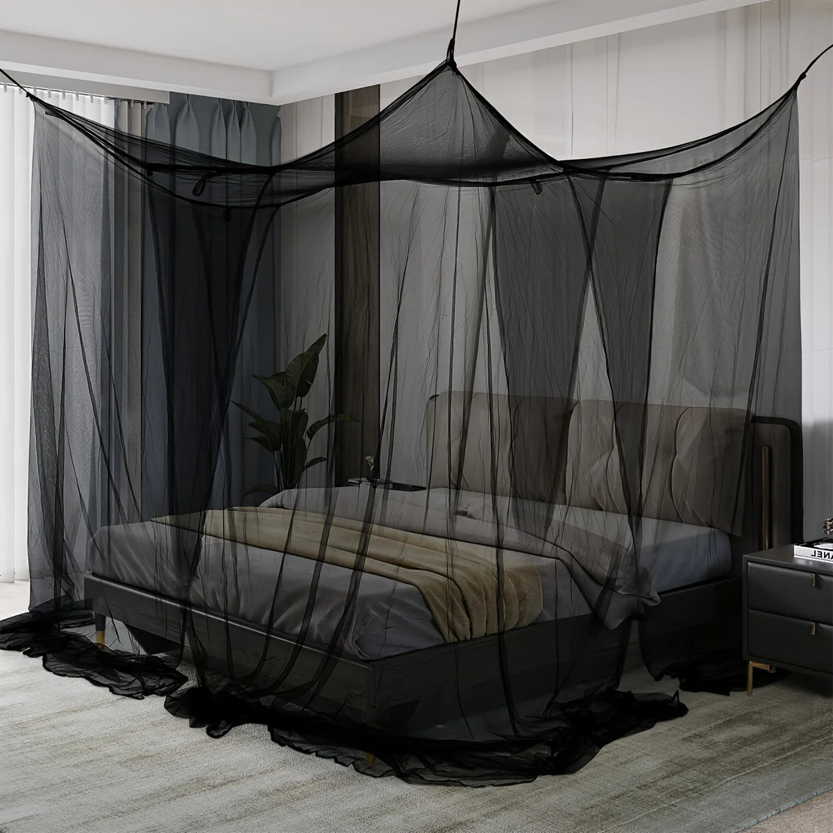 A floor-to-ceiling black mosquito net draped over a bed in a room.