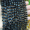 A close-up of black and gold square faceted beads strung together for jewelry making.
