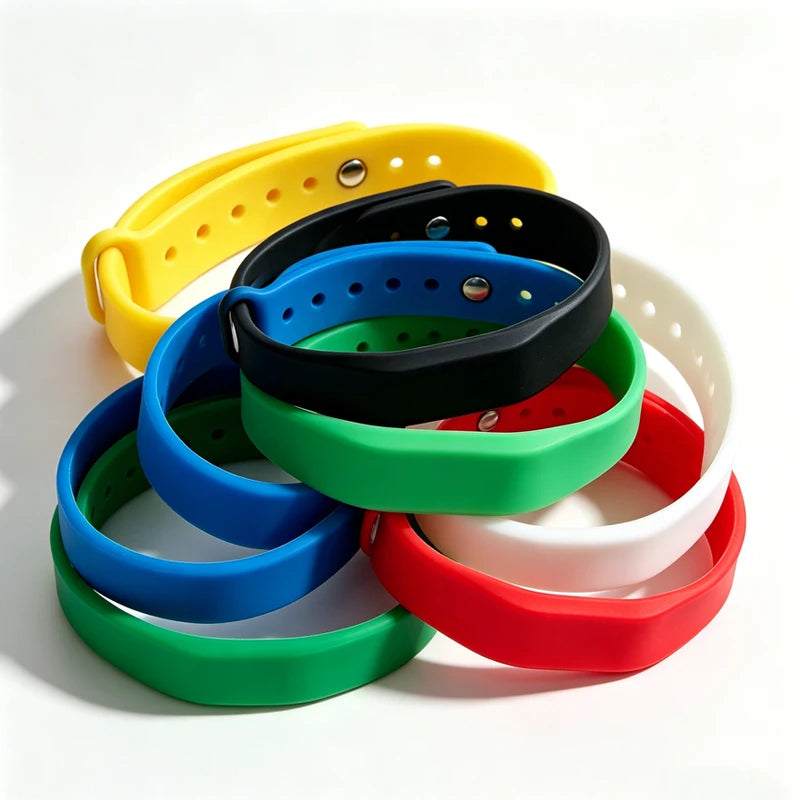 A stack of colorful silicone wristbands in yellow, black, blue, green, red, and white for access control.