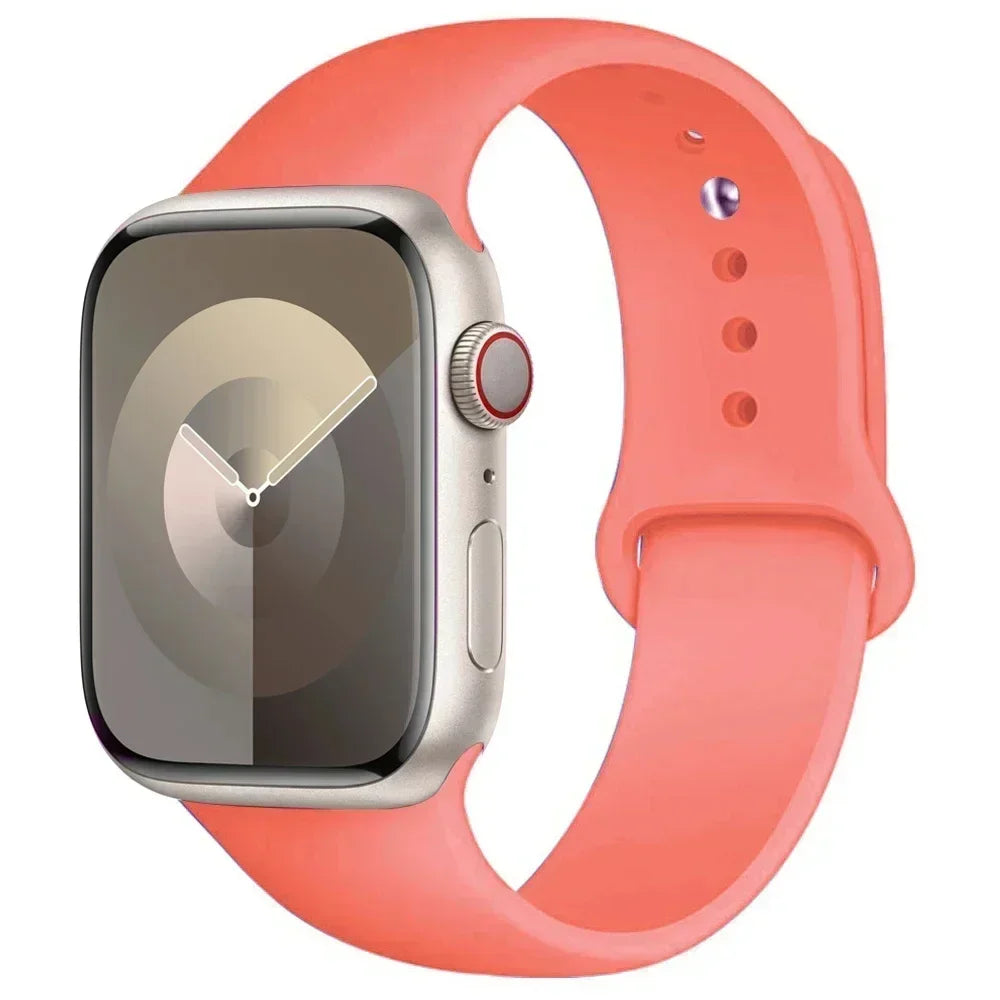 An Apple Watch in a silver case with a bright coral silicone sport band.