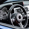 Close-up view of a black steering wheel with a spinner knob and controls inside a car