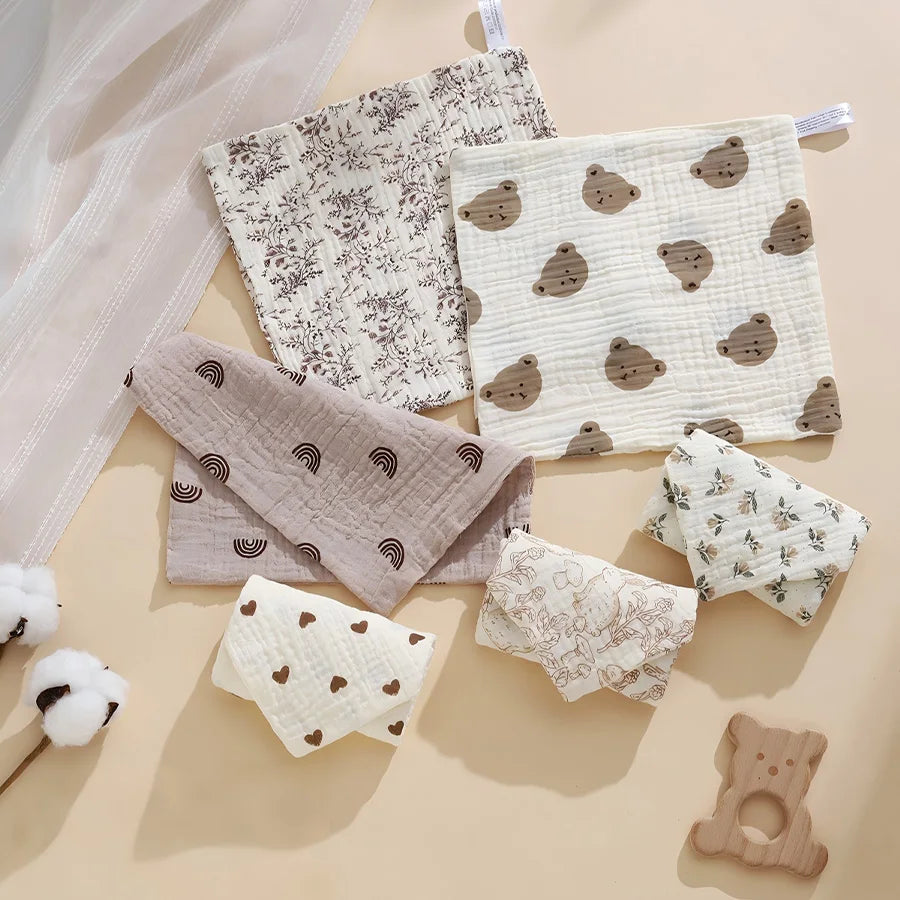 A collection of soft cotton gauze burp cloths featuring various patterns and colors for babies.