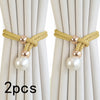 A pair of beige rope and pearl curtain tie-backs are shown against a light fabric background.