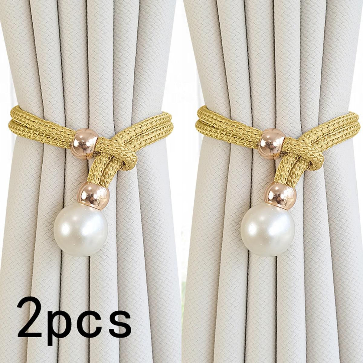 A pair of beige rope and pearl curtain tie-backs are shown against a light fabric background.