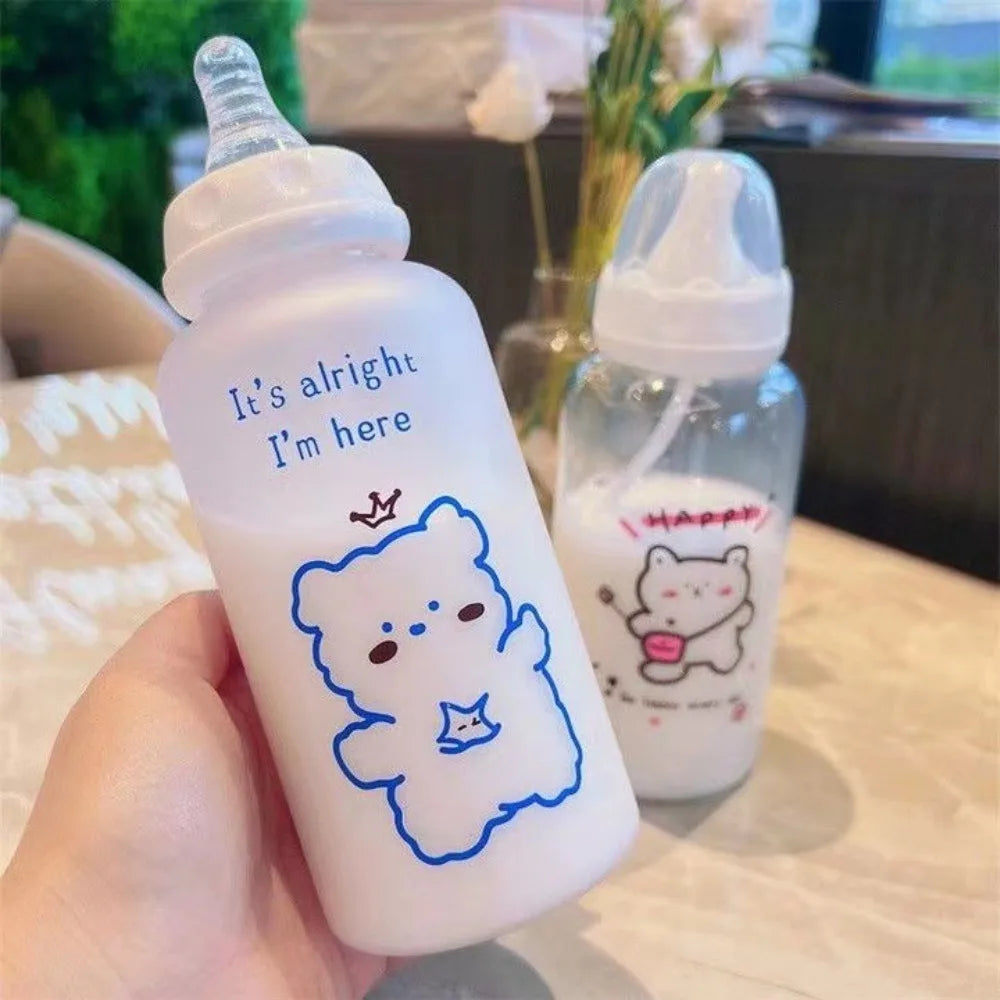 A hand holds a clear plastic bottle with a white cap and a blue outline of a bear, labeled It's alright I'm here.