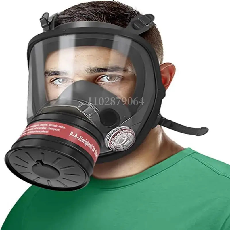 A man wearing a black full face respirator mask with a gas filter canister on his face.