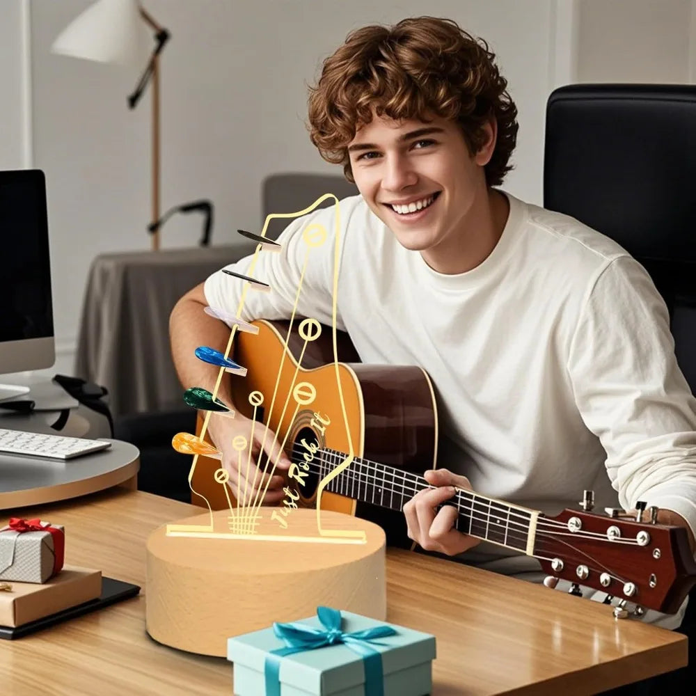A young man holds an illuminated acrylic guitar pick holder with a wooden base on a table.