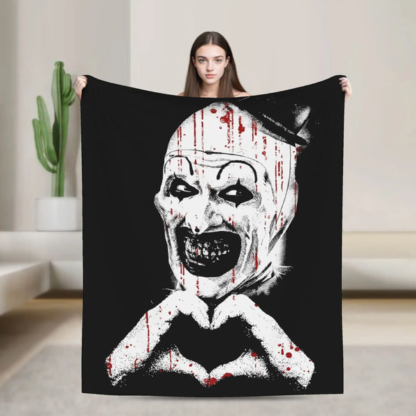 A black throw blanket featuring a distressed white clown face with blood splatters.