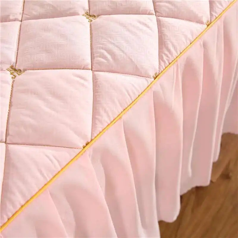 Pink quilted bed skirt with gold embroidery and gathered fabric detail