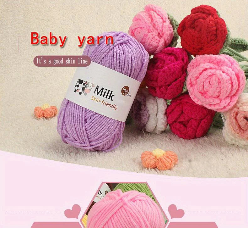 Purple milk colored yarn skein with a label for skin-friendly use surrounded by various pink and red yarn balls.