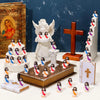 A collection of mini Jesus figurines in various colors and poses arranged on a white surface with books and a wooden cross.