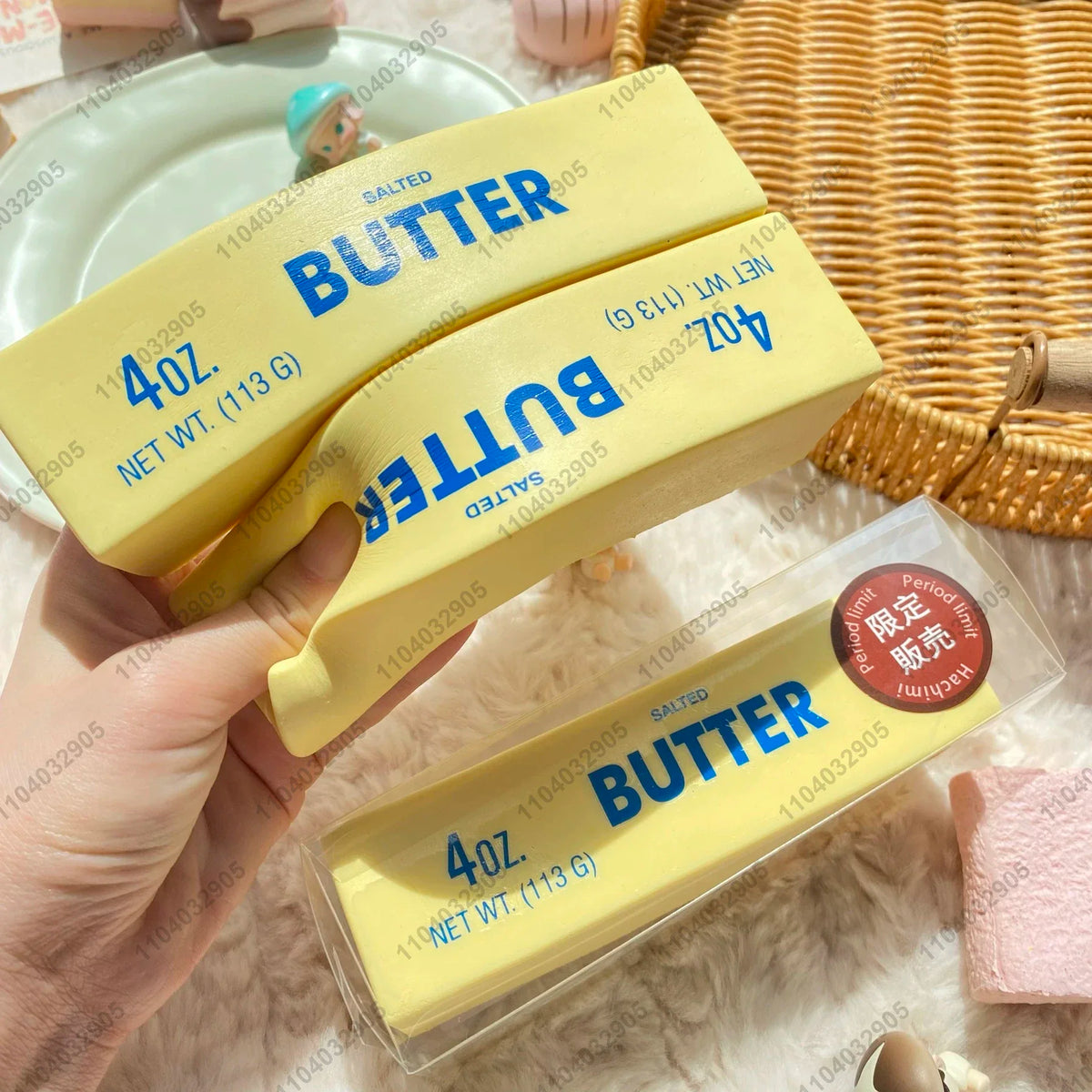 Gelbe Butterriegel, beschriftet als Butter 4 oz gesalzen, werden vor einem geflochtenen Korb gehalten.