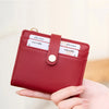 A close-up of a red leather bi-fold credit card wallet with a gold chain and a wooden background.