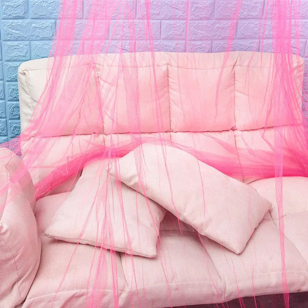 Pink lace canopy mosquito net draped over a pink upholstered bed