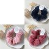 A pair of fluffy pink coil hair ties displayed on a white plate with gold trim.