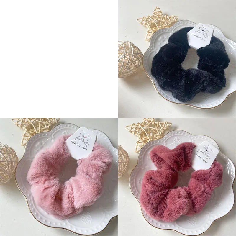 A pair of fluffy pink coil hair ties displayed on a white plate with gold trim.