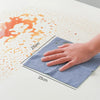 A hand is holding a blue microfiber cleaning towel, demonstrating its 25x25 cm size on a white surface.
