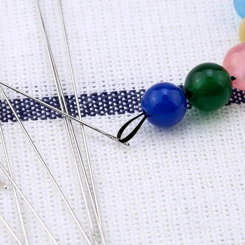 Stainless steel beading needles with colorful beads on a white background