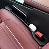 A pink car seat with a black gap filler and storage organizer visible in the interior