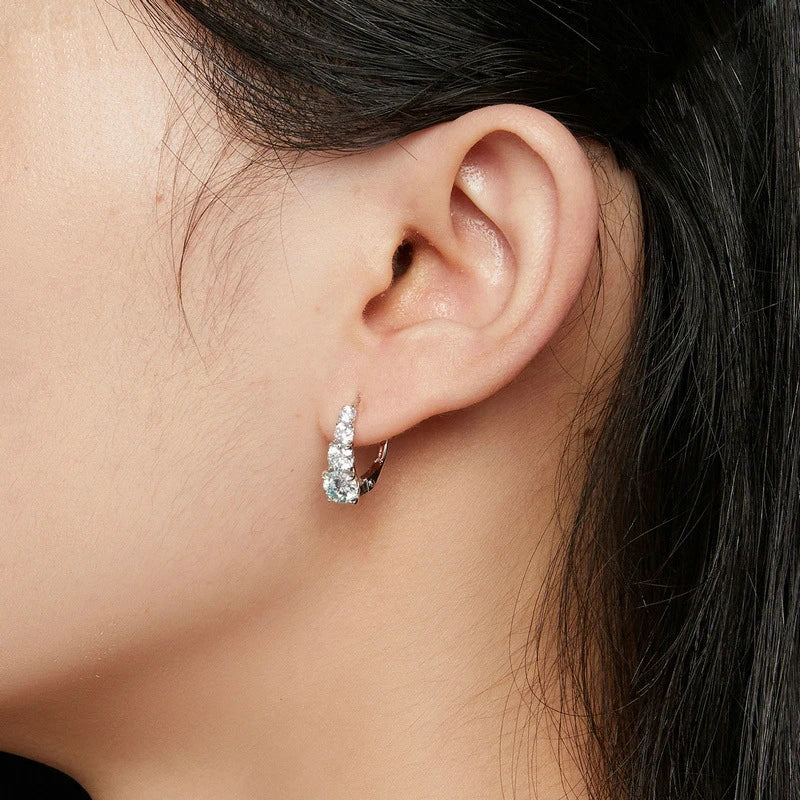 Gros plan sur l'oreille d'une femme avec un clou d'oreille et un cluster de pierres claires.