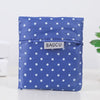 A folded blue fabric shopping bag with white polka dots resting on a white surface.