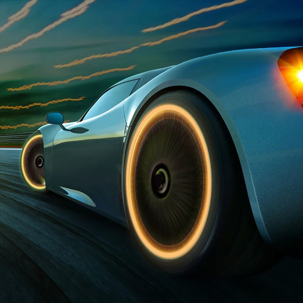A silver sports car drives on a road at dusk, showing the glowing rim of a tire.