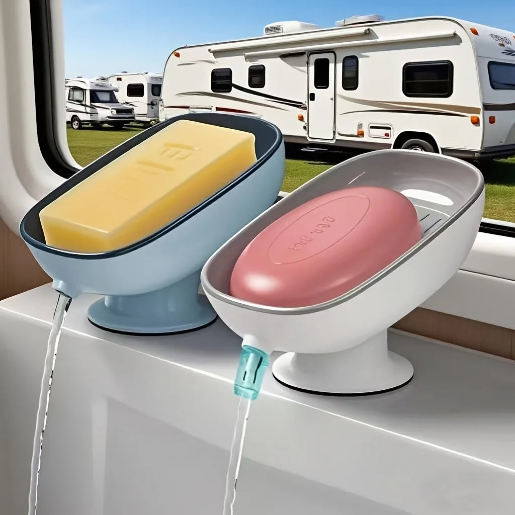A white suction cup soap dish with a draining tray and a pink soap are shown on a windowsill.