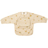 A beige waterproof long-sleeve smock for toddlers with a pocket and small yellow fruit print.