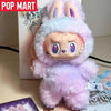 A fluffy purple Labubu plush doll with pink ears and a hood is shown in a product box.