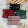 A collection of four compact PU leather coin purses in shades of black, red, green, and pink, displayed on a white background
