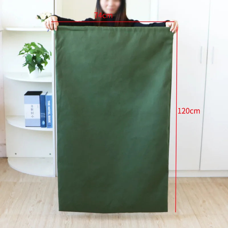 A person holds up a large, dark green heavy-duty canvas laundry bag with a drawstring closure.