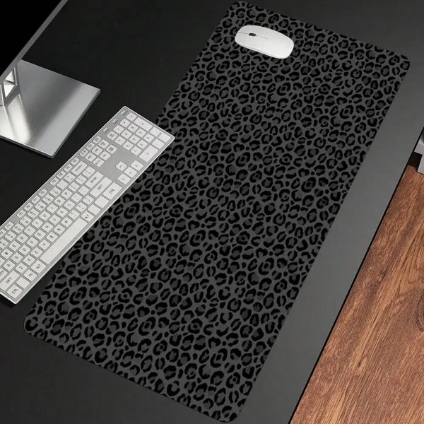 A black mouse pad with a wild leopard print design is shown next to a white computer mouse and keyboard.