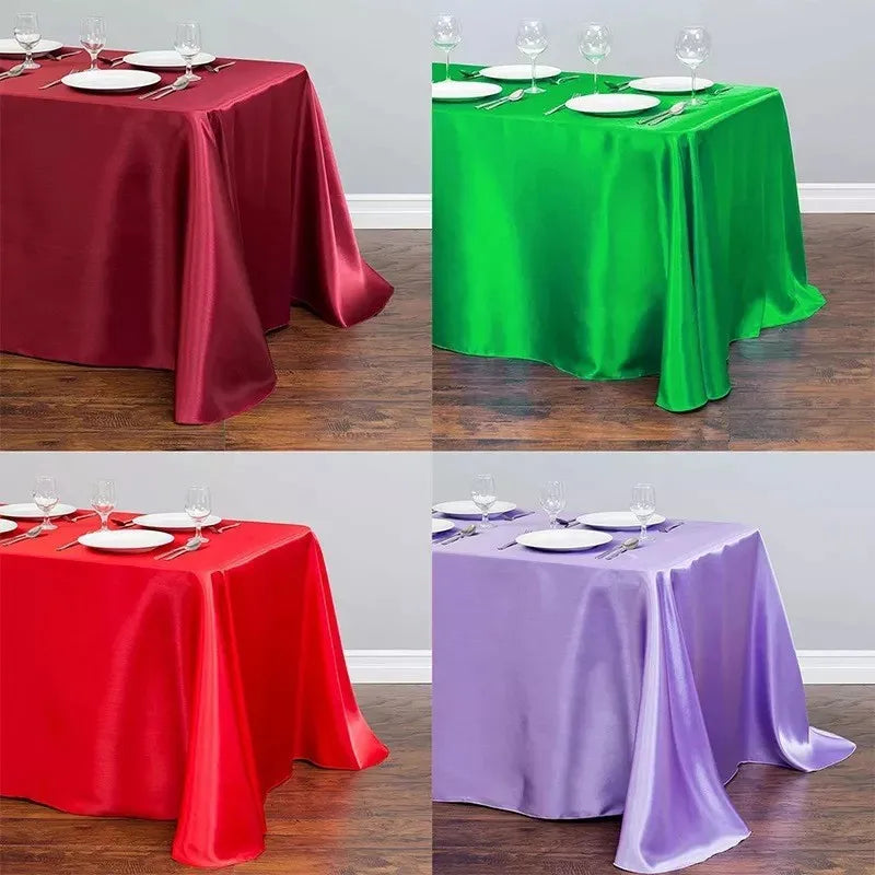 Three satin tablecloths in burgundy, emerald green, and lavender colors displayed on a wooden floor.