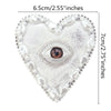 A heart-shaped patch featuring a sparkling silver background and a central realistic eye design surrounded by pearl beads.