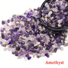 A pile of purple and clear amethyst crystal stone chips in a black bowl.
