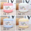 Six skeins of soft cotton yarn in various colors including pink, white, light blue, and creamy yellow.