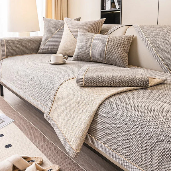 Beige rutschfeste Sofabezug mit strukturiertem Stoff und Zierrand auf einem modernen Sofa.