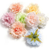 A cluster of lifelike silk peony flower heads in shades of pink, peach, and cream.