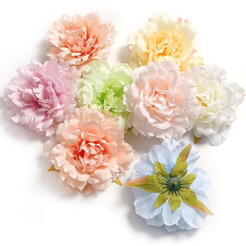 A cluster of lifelike silk peony flower heads in shades of pink, peach, and cream.