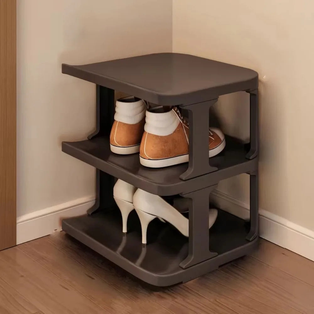 A dark gray stackable vertical shoe rack with three tiers holding various pairs of shoes.