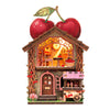A miniature wooden book nook display featuring a fruit-themed scene with LED lighting and a large apple on top.