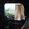 A plaid sun shade curtain with a bear design is shown hanging in the window of a car.