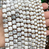 A close-up of natural stone square faceted beads in white and gray marble colors being held in a hand.