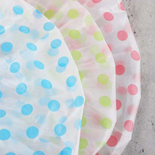 A stack of three disposable waterproof shower caps with various polka dot patterns.