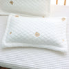 A white quilted baby pillow with a removable ice silk cover resting on a white textured surface.