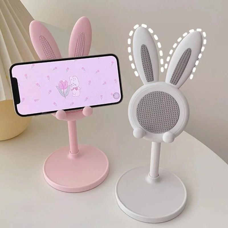 A pink rabbit-shaped stand holds a smartphone displaying a floral design.