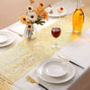 Metallic gold glitter table runner set with wine glass, fruit, and silverware for a wedding or party setting.