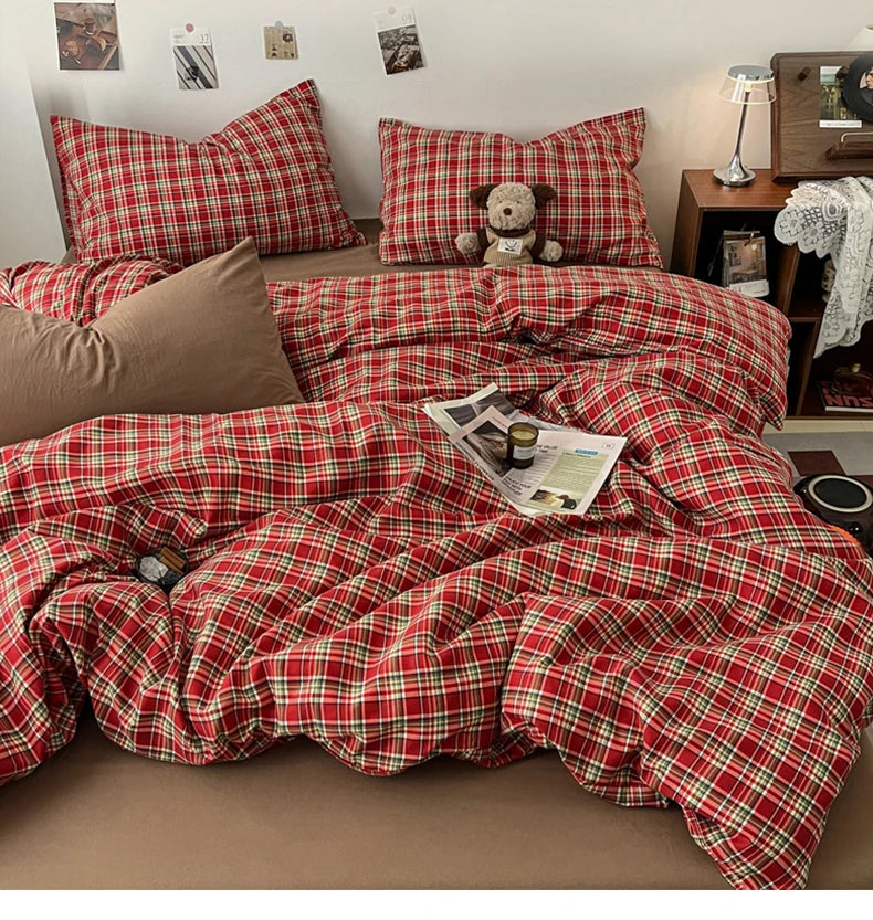 A red plaid duvet cover set with a matching quilt and pillows displayed on a bed.
