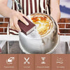 A hand is using a brown cleaning sponge to scrub a stainless steel pot in a kitchen setting.